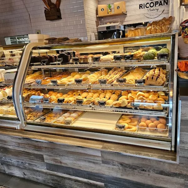 A glass display case filled with various baked goods and pastries at Ricopan Bakery.