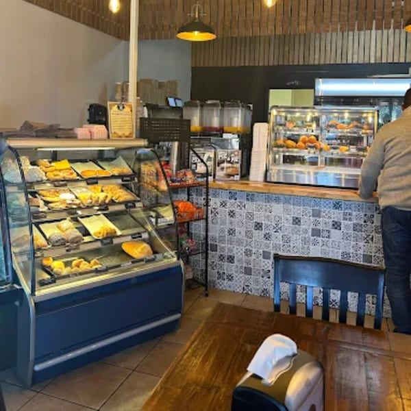 Bakery interior with display cases full of pastries, a tiled counter, and a person standing at the counter.