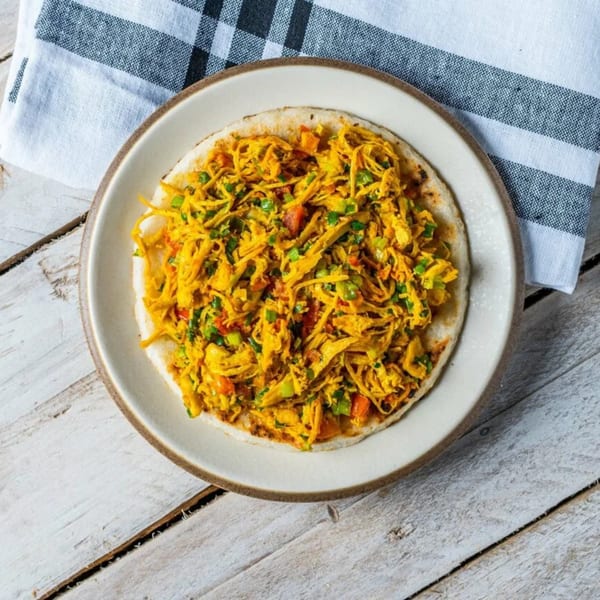 Arepa Reina Pepiada, a Venezuelan dish with shredded chicken and avocado, on a white plate.